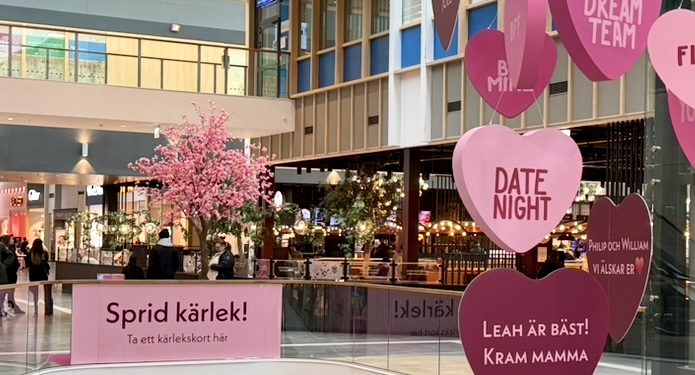 Hjärtan hänger i taket, ett rosa träd står i bakgrunden och texten Sprid kärlek! syns.