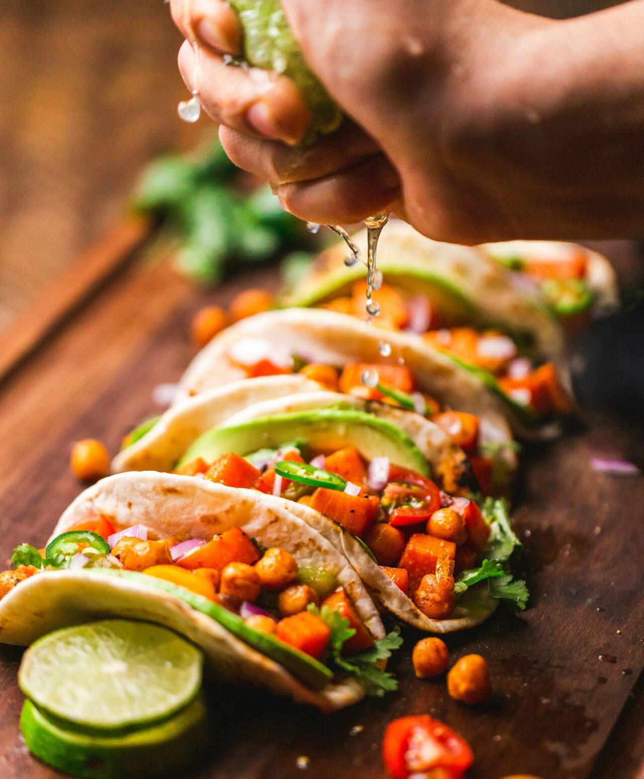 Någon pressar över lime på små tacos.